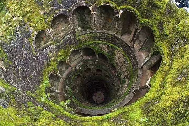 Moss-covered spiral staircase at Quinta da Regaleira, Sintra, featured on a full-day tour with Pena Palace entry and pickup.