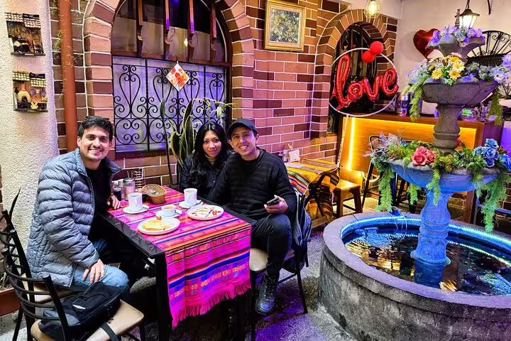 Travelers enjoying a Quito food and cacao tasting tour in a charming cafe with colorful decor and a decorative fountain.