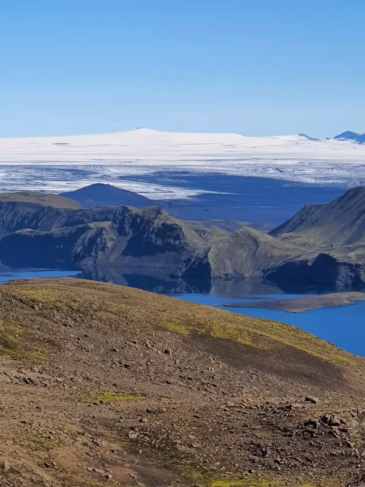 Dramatic rocky canyon with glacier and snow-capped mountains under clear blue sky in Iceland Highlands