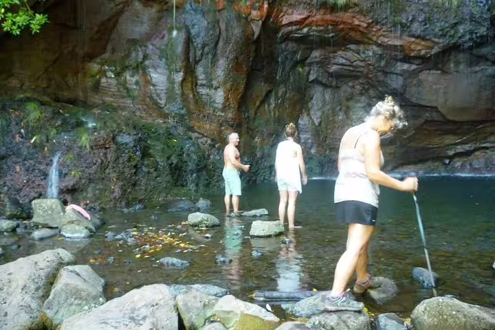 Visitors explore the serene rock pool and waterfall at Rabaçal's 25 Fontes, a highlight of Madeira's scenic nature trails.