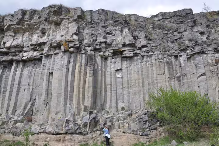 Tall basalt columnar rock formations at Racos with a person standing at the base for scale