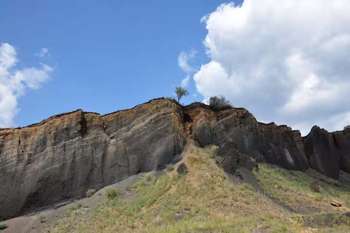 Eroded volcanic rock cliffs with sparse vegetation at Racos, Transylvania, under a blue sky