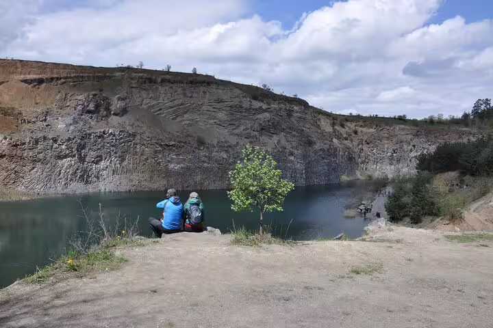 Two hikers sitting by a turquoise quarry lake at Racos volcanic crater, Brasov region