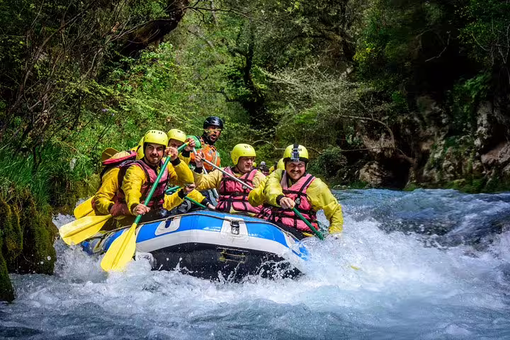 Rafting through Alfeios River rapids in Lousios Gorge, Greece, with helmets and guide on adventure tour