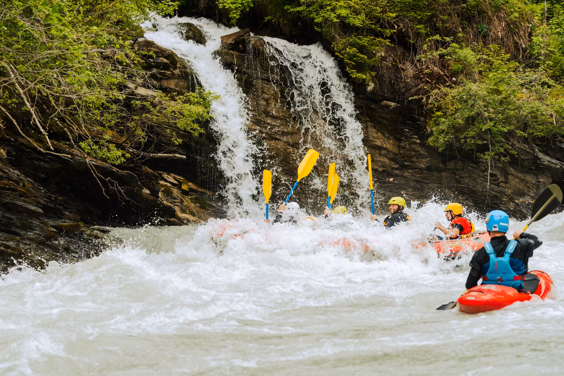 Adventurers tackle rapids near a waterfall during a thrilling rafting trip in Interlaken's whitewater action tour.