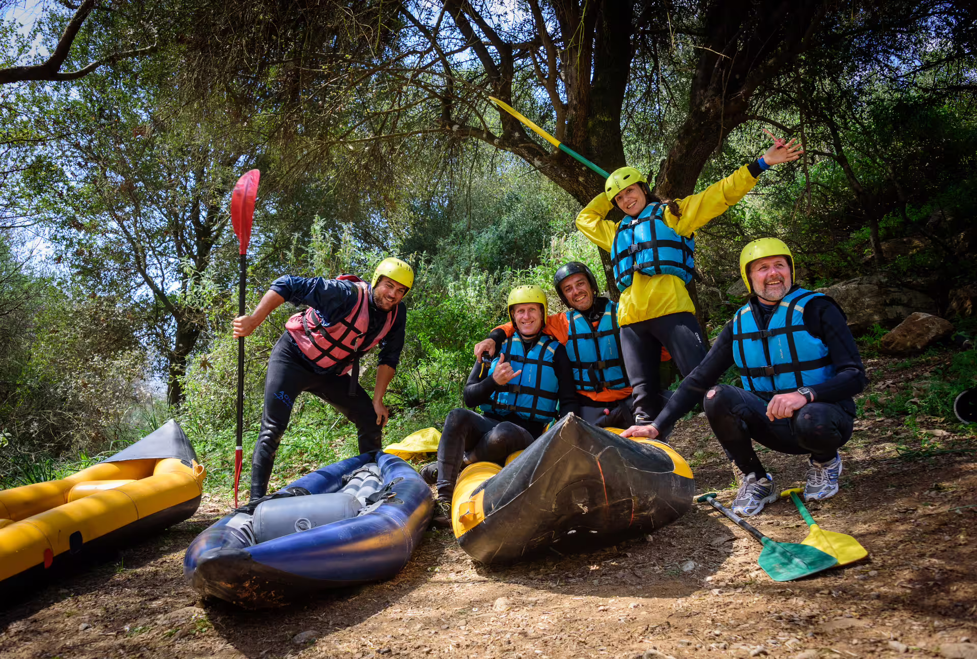Rafting team posing with helmets, paddles and inflatable rafts before the Lousios and Alfeios rivers tour in Greece