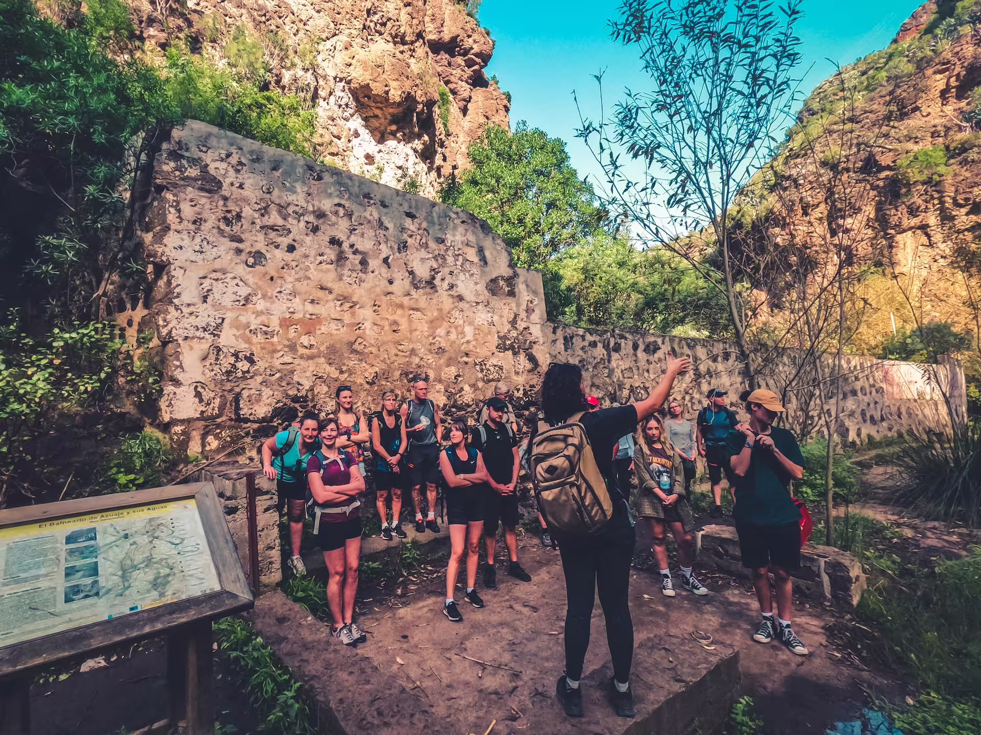 Tour group listens to a guide near ancient ruins in a rainforest, part of The Rainforest Tour - Small Group Trip.