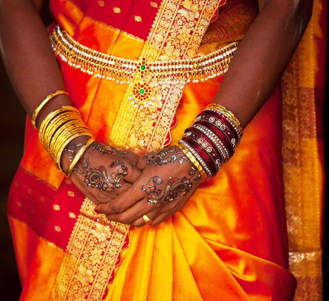 Close-up of intricate henna designs and traditional bangles on a vibrant saree, showcasing Rajasthan's cultural elegance.