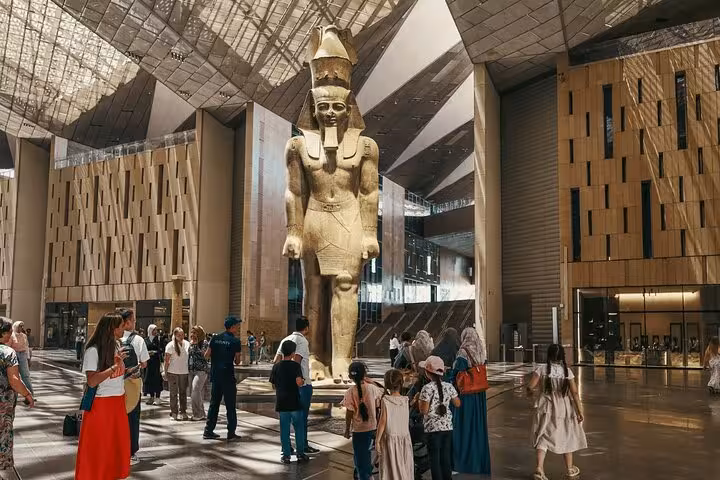 Visitors beneath the Ramses II statue in the Grand Egyptian Museum atrium on a guided Cairo tour