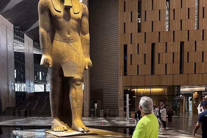 Visitor admiring the colossal Ramses II statue inside the Grand Egyptian Museum on a Giza Pyramids tour