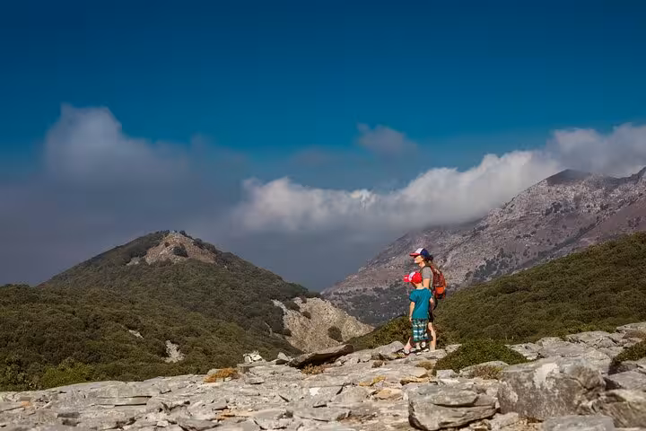 Family hikers pause on rocky Randi Forest trail overlooking Ikaria mountains during Seychelles beach and boat day trip