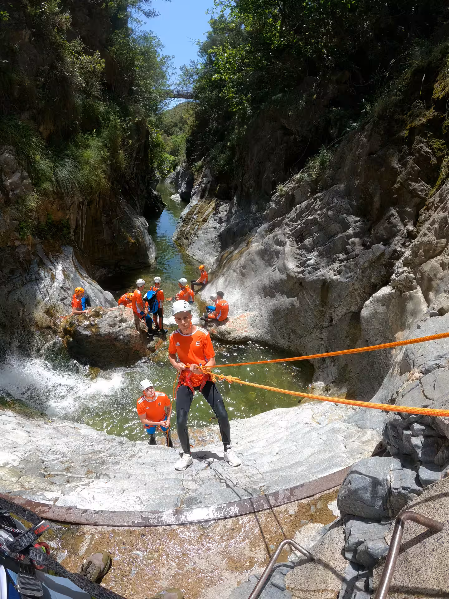 Group of adventurers rappelling down rocky cliffs during a guided canyoning tour in Guadalmina Canyon Estepona