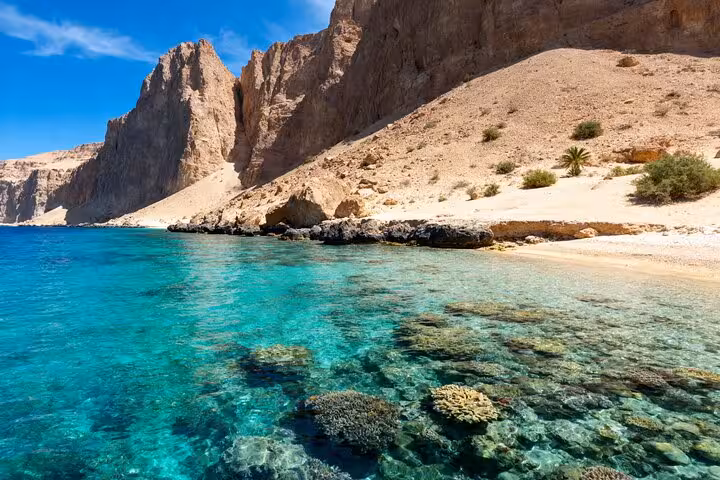 Crystal-clear Ras Mohammed lagoon with coral reef shoreline, snorkel stop on half-day bus tour from Sharm