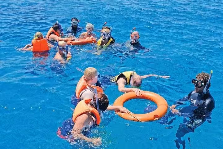 Group snorkeling with guide in Ras Mohammed National Park, Sharm El Sheikh, Red Sea with safety ring