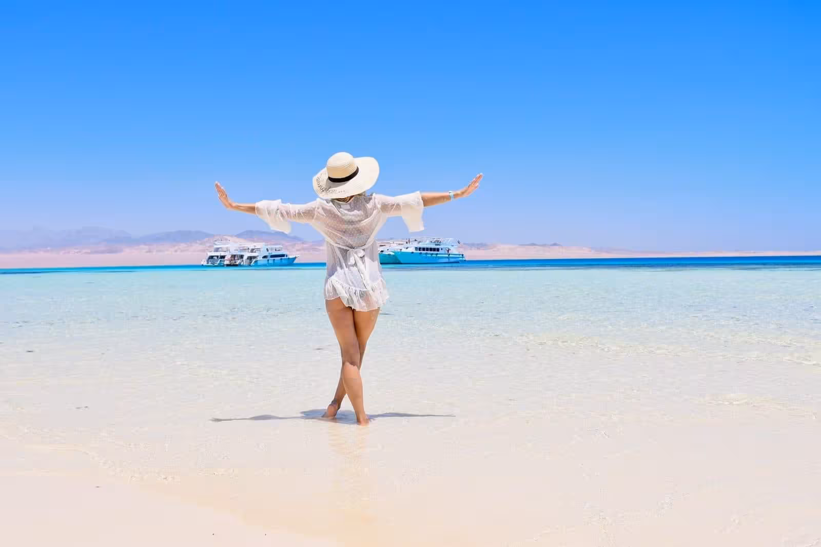 Traveler on White Island sandbar with boats in the Red Sea, Ras Mohammed snorkeling day trip from Sharm