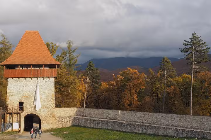 Rasnov Fortress stone tower with orange roof surrounded by autumn trees and misty mountains
