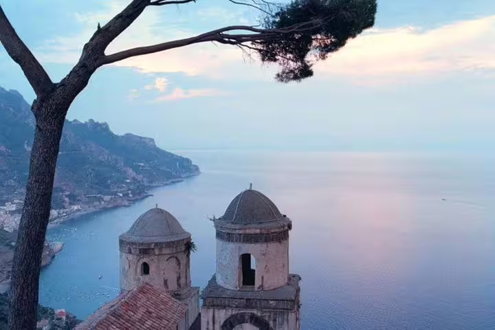 Sunset view from Ravello over the Amalfi Coast, with historic church domes, pine tree and calm Tyrrhenian Sea below