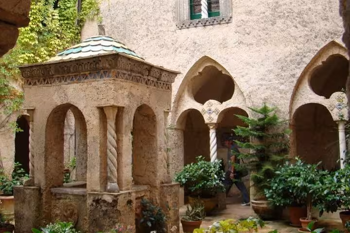 Charming courtyard in Ravello with ancient architecture and lush greenery, perfect for a half-day tour discovery.