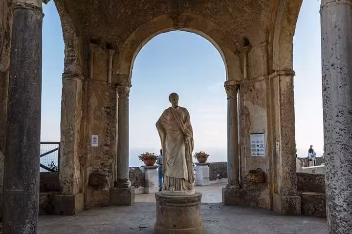 Historic statue framed by ancient arches overlooking the sea in Ravello, a highlight of the half-day tour experience.