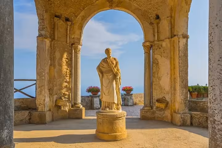 Historic statue framed by ancient arches in Ravello, offering a glimpse of the serene Amalfi Coast backdrop.