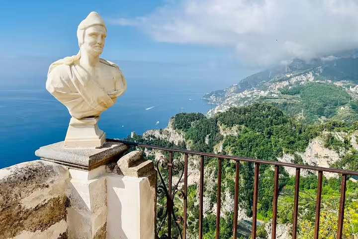 Marble bust on terrace overlooking Amalfi Coast cliffs and blue sea in Ravello, Italy