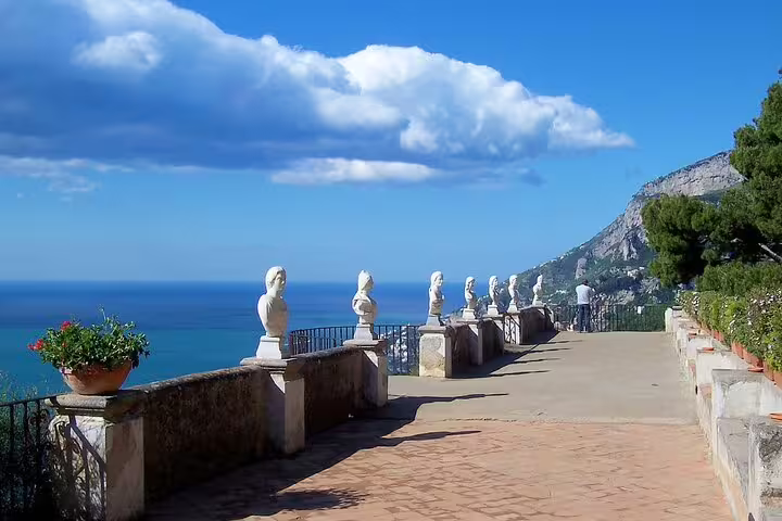 Scenic terrace with white bust sculptures overlooking the blue Amalfi Coast sea in Ravello