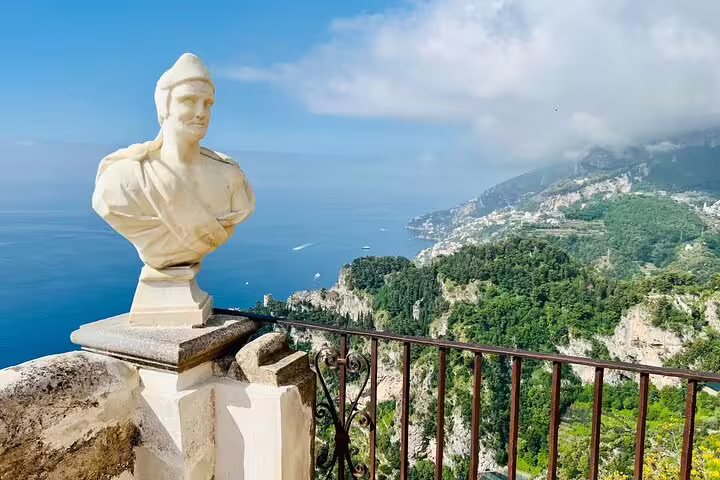 Marble bust statue at Villa Cimbrone terrace overlooking Amalfi Coast cliffs and blue sea, Ravello