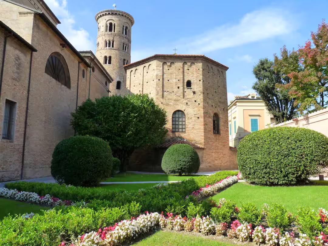 Lush garden and ancient brick basilica in Ravenna with round bell tower, a highlight of the 3-hour private walking tour