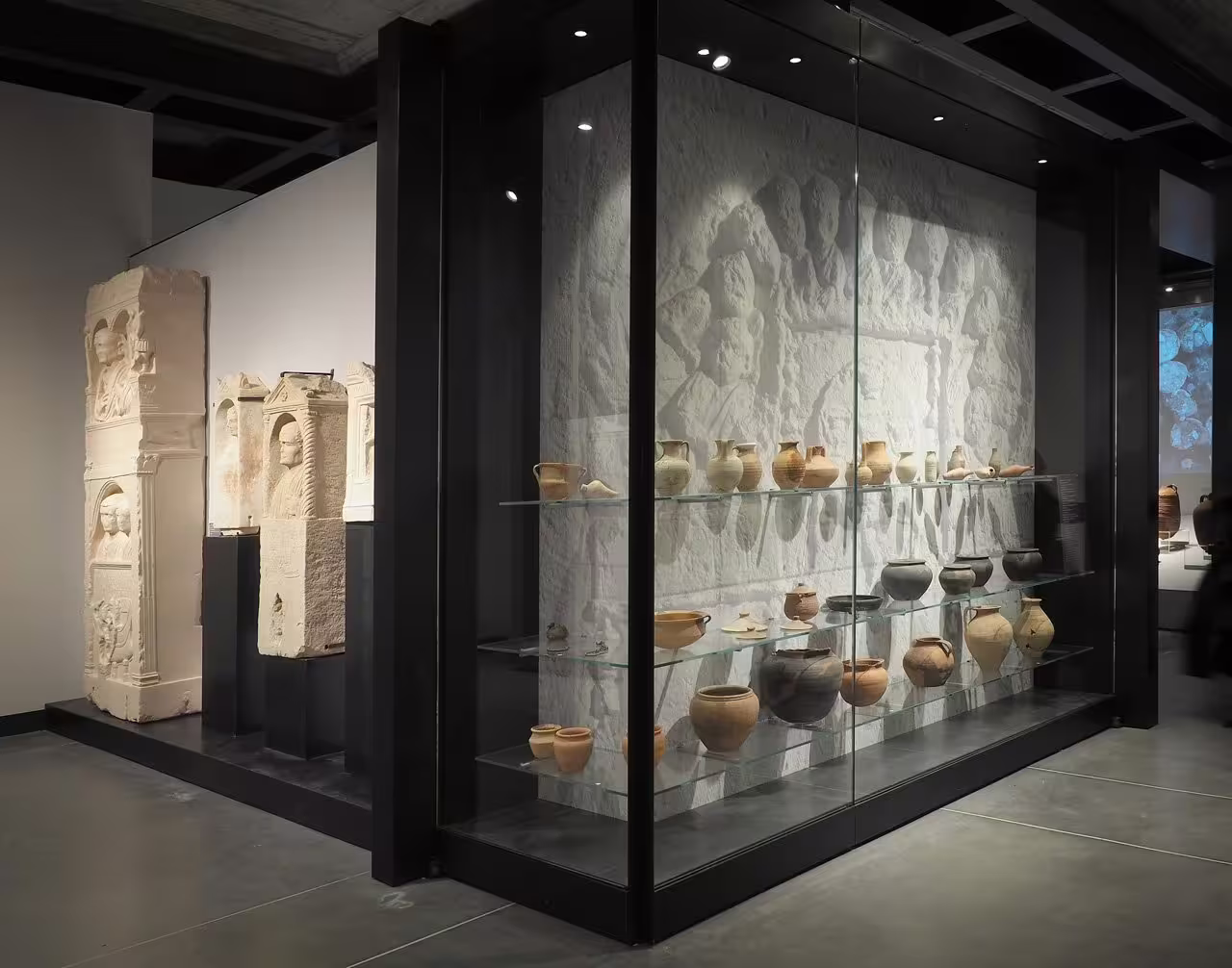 Glass display of Roman pottery and carved stone reliefs at Ravenna Classis Museum with entry ticket access