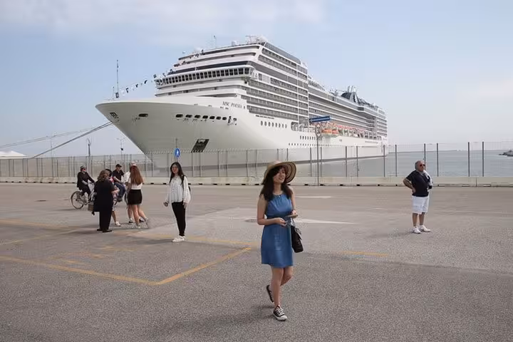 Cruise passengers at Ravenna terminal preparing for luxury transfer to Venice with cruise ship in background.