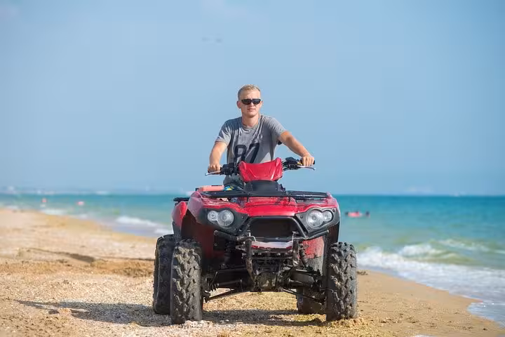 Rider on red ATV quad along Hurghada beach, Red Sea coastline adventure combining sand, sea and desert views