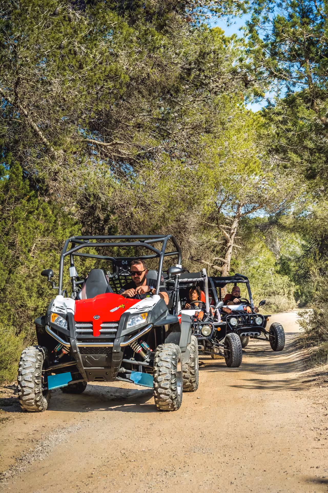 Red off-road buggy leading group through pine forest on Ibiza day trip, southern Ibiza nature and Salinas tour