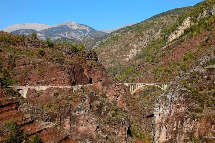 Scenic view of the Red Canyon with a historic stone bridge, featuring vibrant red rock formations and lush greenery.