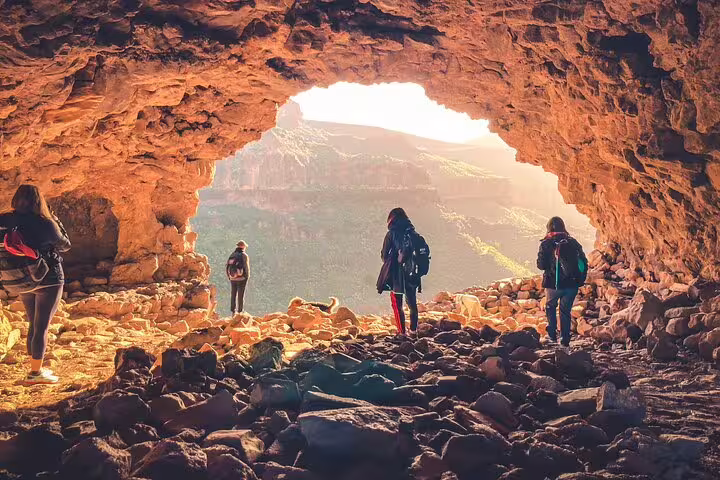 Tourists admire the breathtaking view from a cave opening during the Red Canyon small group adventure.