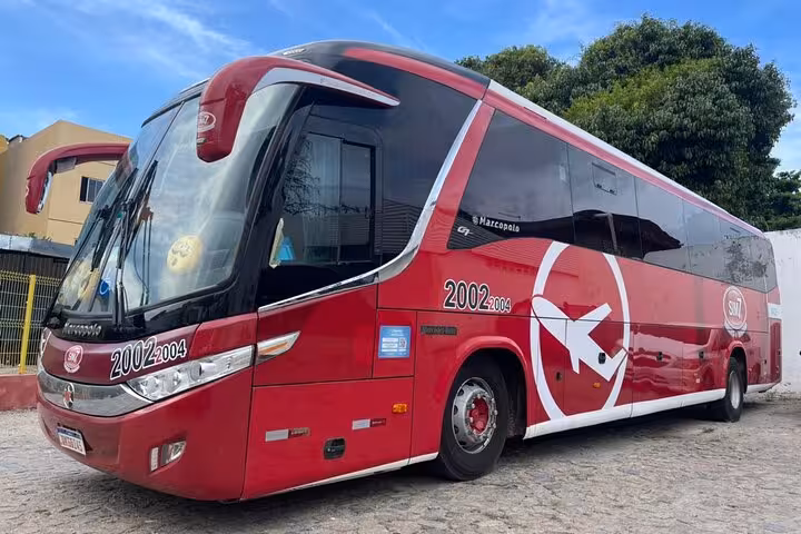 Red coach bus for transfer from Jericoacoara to Fortaleza, comfortable shared shuttle transport in Ceará