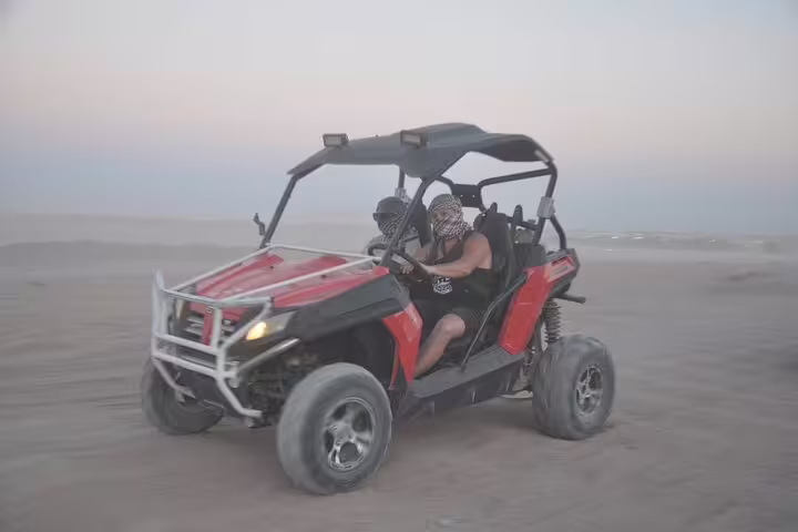 Couple driving red dune buggy across Sinai desert on family buggy adventure safari from Sharm El Sheikh