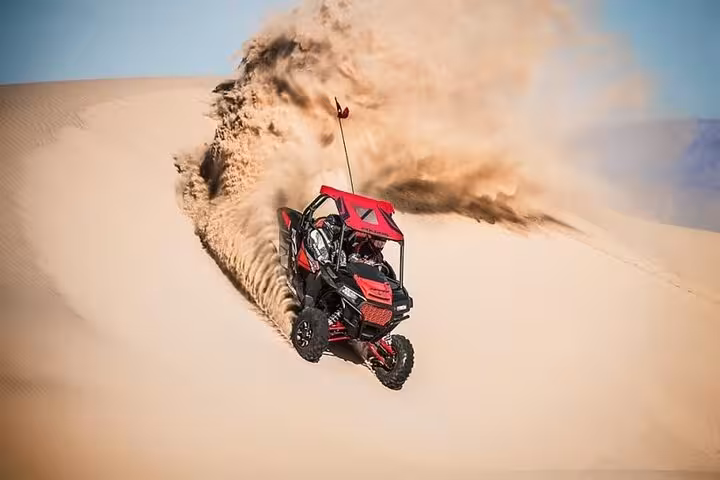 Red dune buggy carving sand wave on Dubai dunes, thrilling evening desert safari off-road adventure