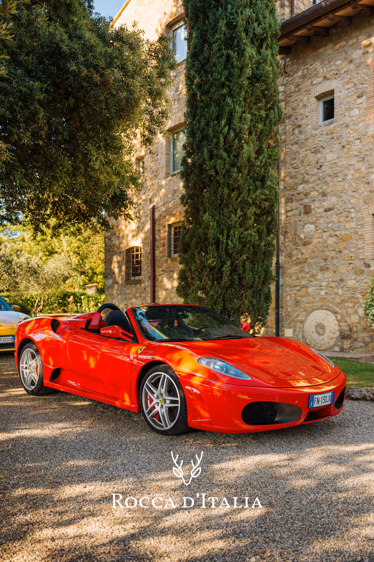 Red Ferrari F430 Spider convertible parked at a Tuscan stone villa in Chianti, Italy