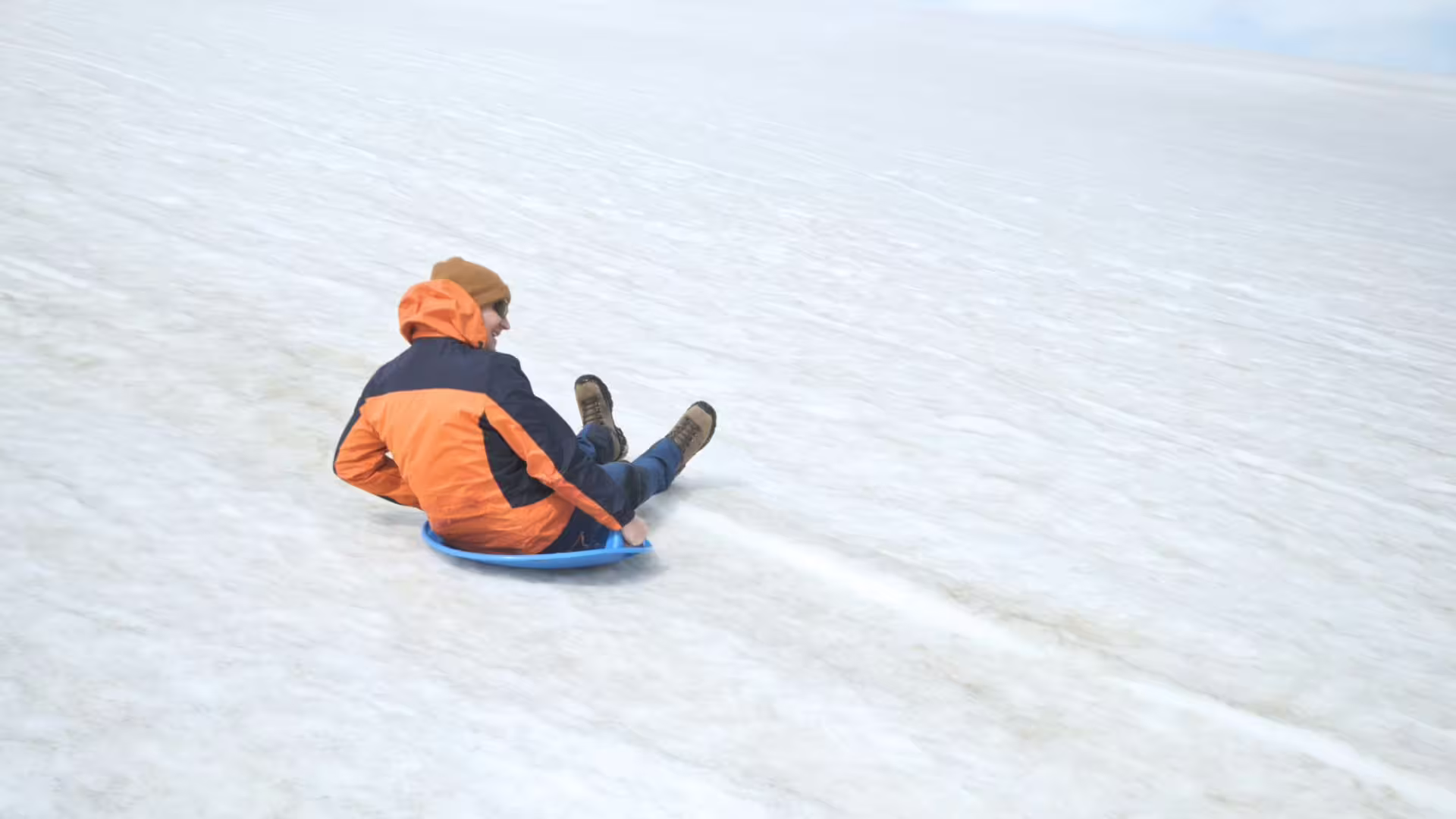 Traveler sledding on Langjökull glacier snow during Red Glacier Monster Truck Tour from Gullfoss, Iceland