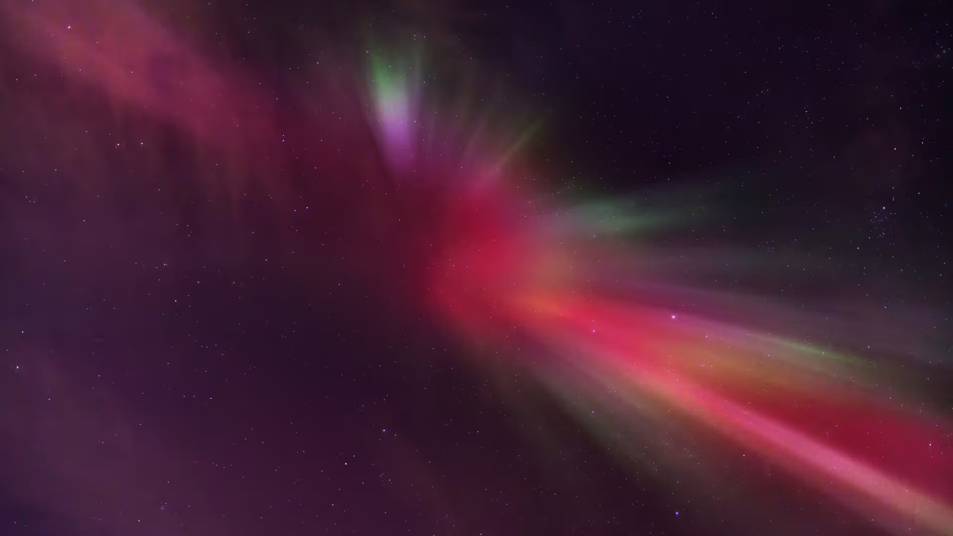 Vivid red and green northern lights aurora borealis swirling across a starry night sky in Iceland