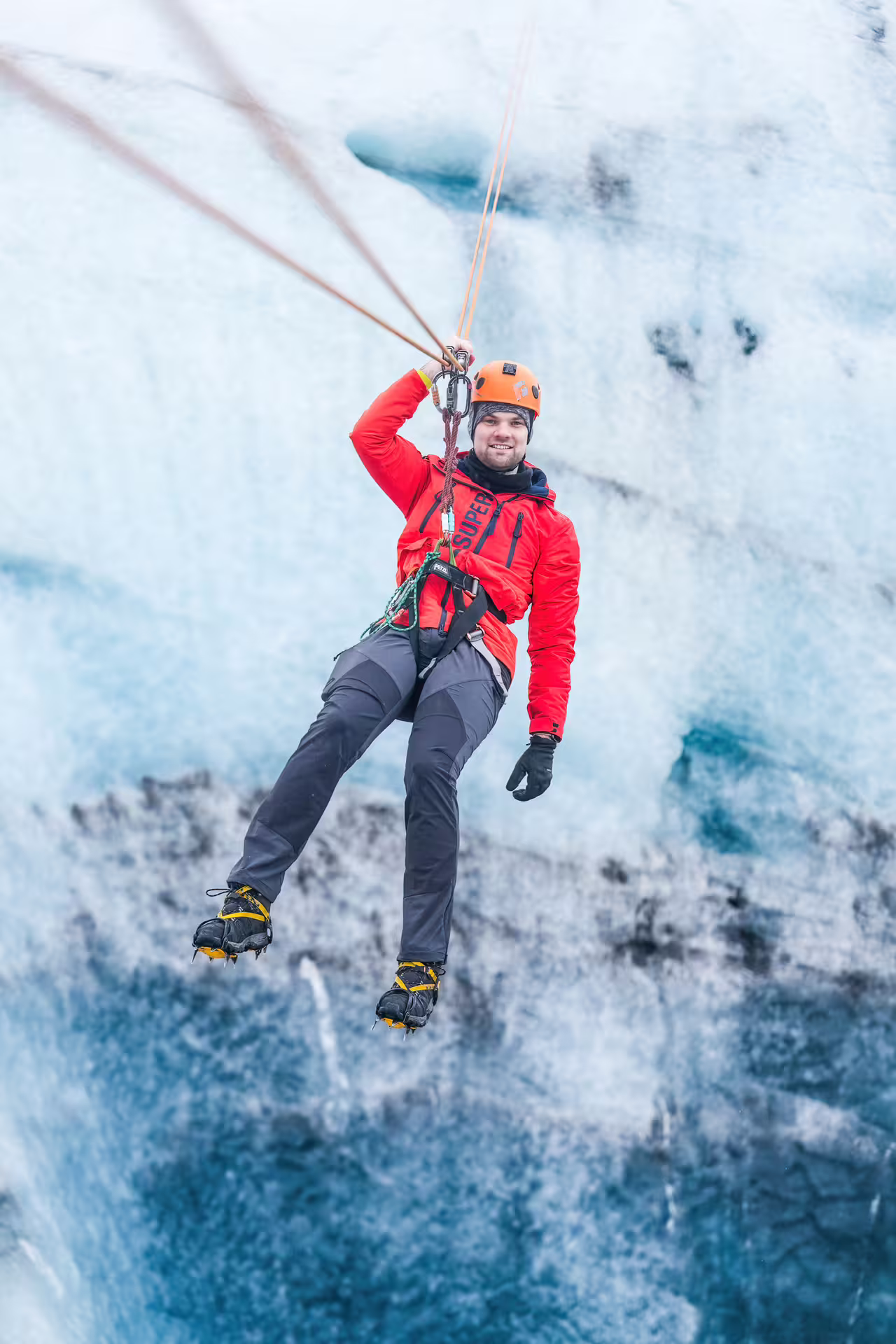 Adventure climber in red jacket and crampons ice climbing on South Coast glacier hike tour in Iceland summer