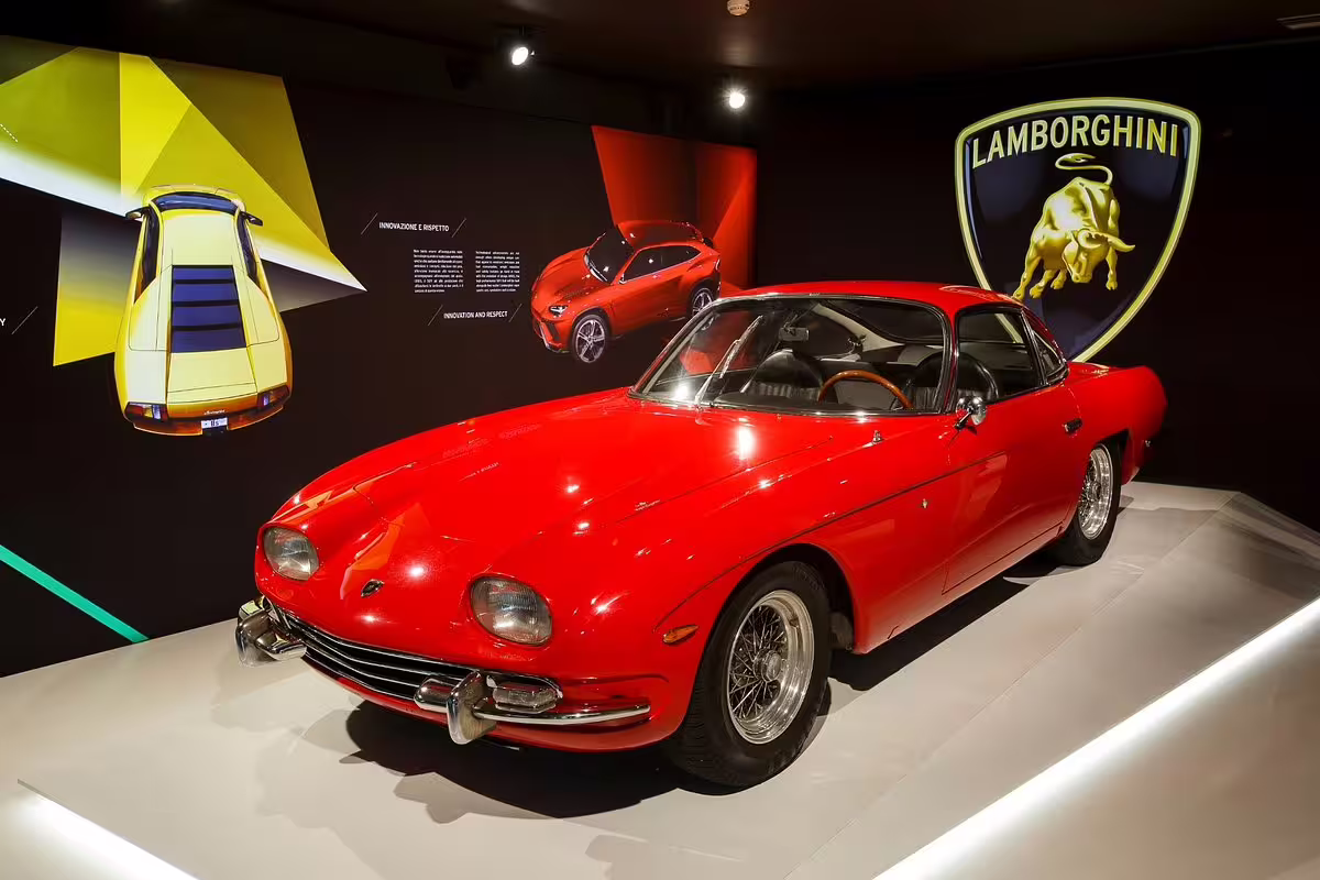 Red classic Lamborghini on display at Museo Lamborghini near Bologna, Italy, with iconic bull logo backdrop