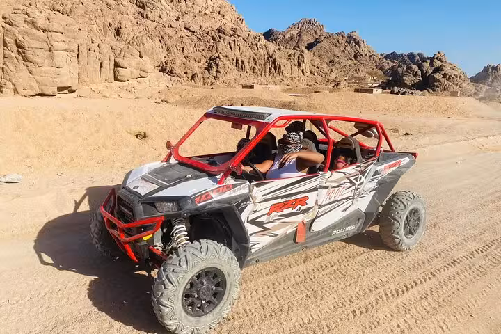 Family car buggy in Sharm El Sheikh desert, red Polaris RZR driving by rocky Sinai mountains