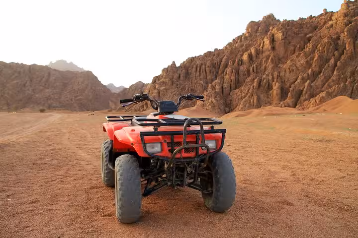 Red quad bike parked in Hurghada desert canyon, part of ATV safari with hotel transfer and BBQ dinner