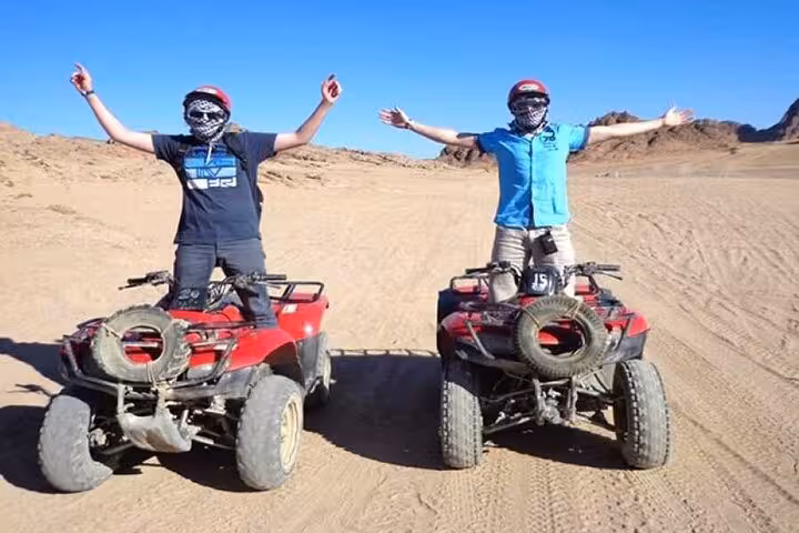 Two riders on red quad bikes in the desert during a 5-hour super safari ATV buggy tour with jeep and BBQ show
