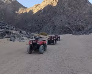 Red quad bikes lined up on sandy desert trail with rocky mountain backdrop in Hurghada
