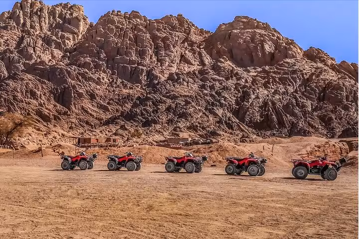 Line of red quad bikes ready for a Sharm El Sheikh ATV safari in the Sinai desert mountains at golden hour