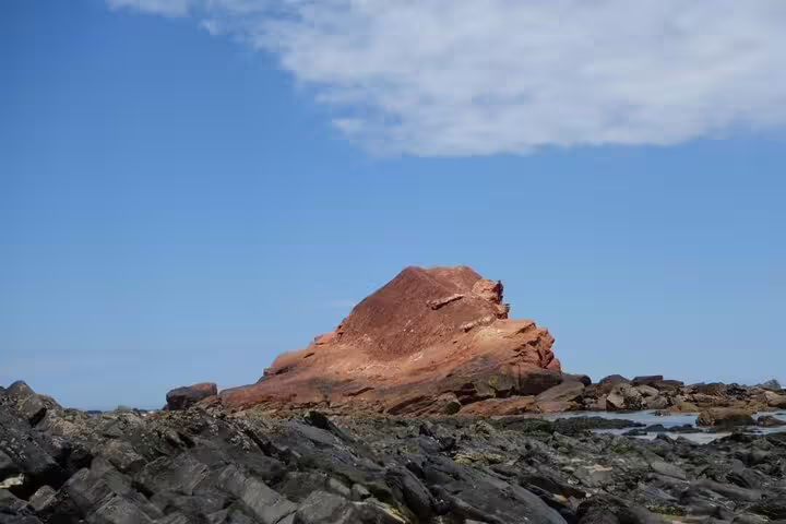 Dramatic red rock formation under a blue sky in Algarve Natural Park, highlighting the region's unique geological features.