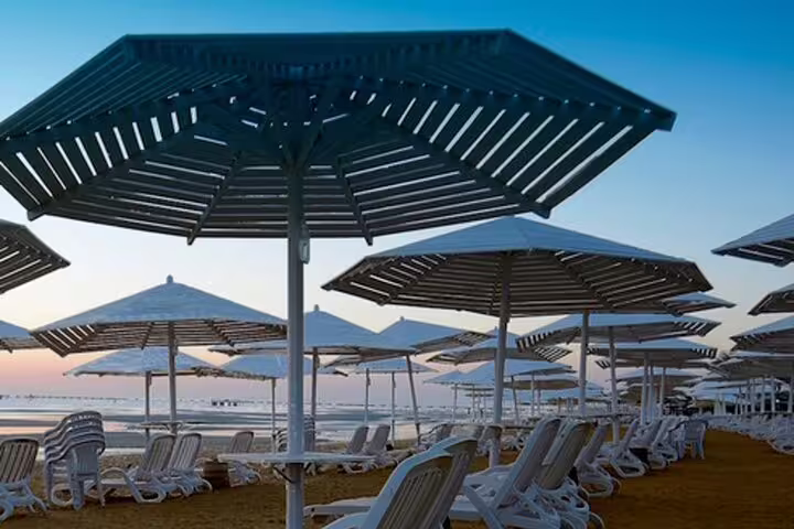 Red Sea beach resort sun loungers and umbrellas at sunset, relaxing finale of 4-day Cairo and Red Sea package