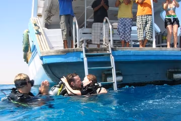 Divers celebrating at the surface beside a Red Sea liveaboard boat ladder in clear Egypt waters